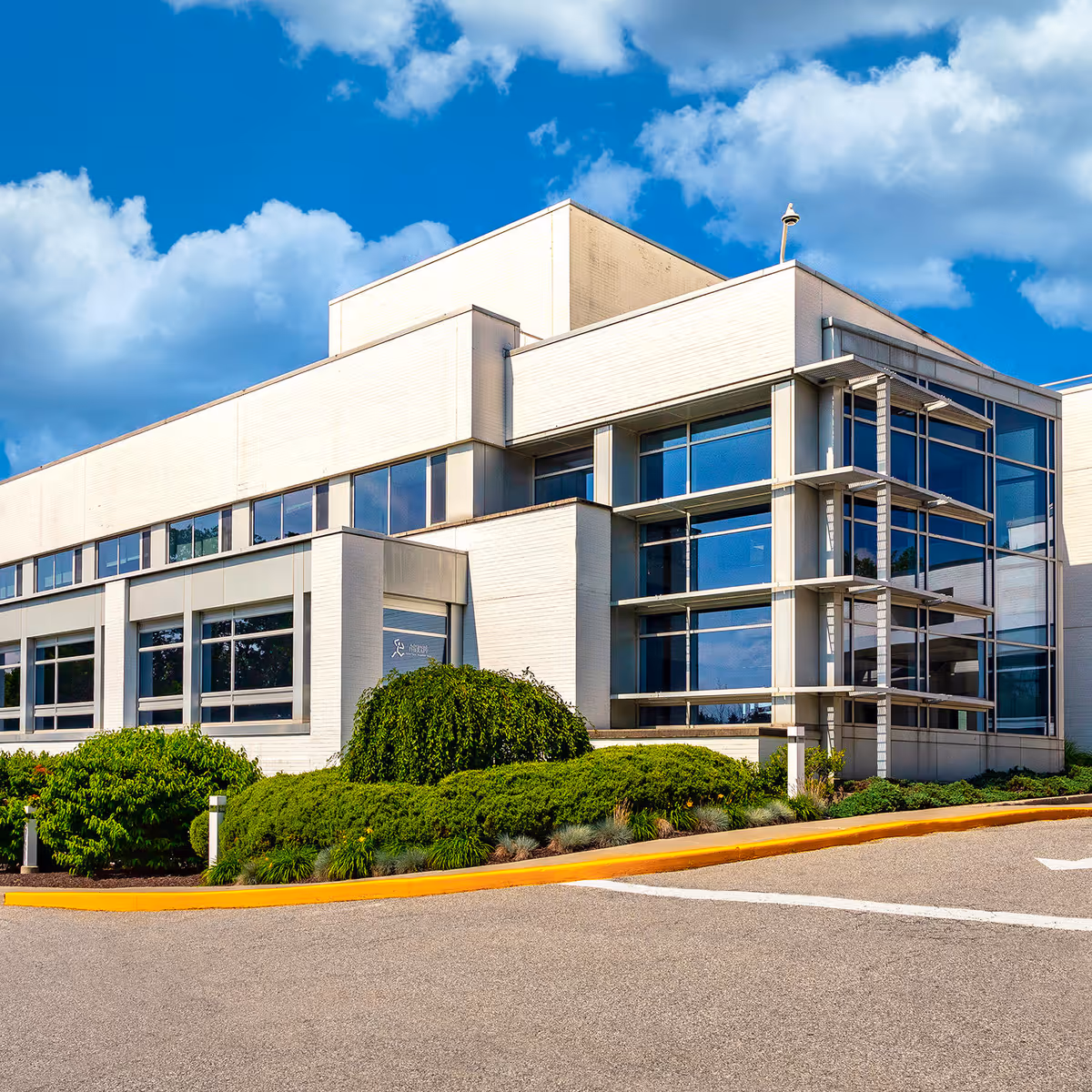 Modern medical building exterior with large windows and landscaped shrubs.