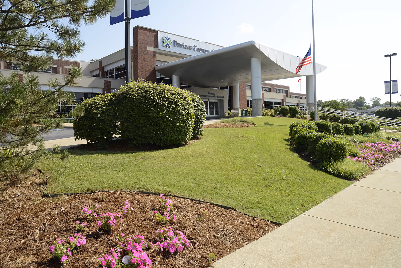 Exterior view of Daviess Community Hospital with entrance canopy, manicured lawn, and flags.