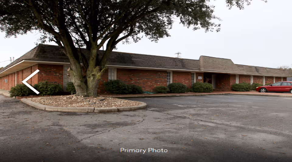 Exterior view of a single-story brick facility with a surrounding parking lot.