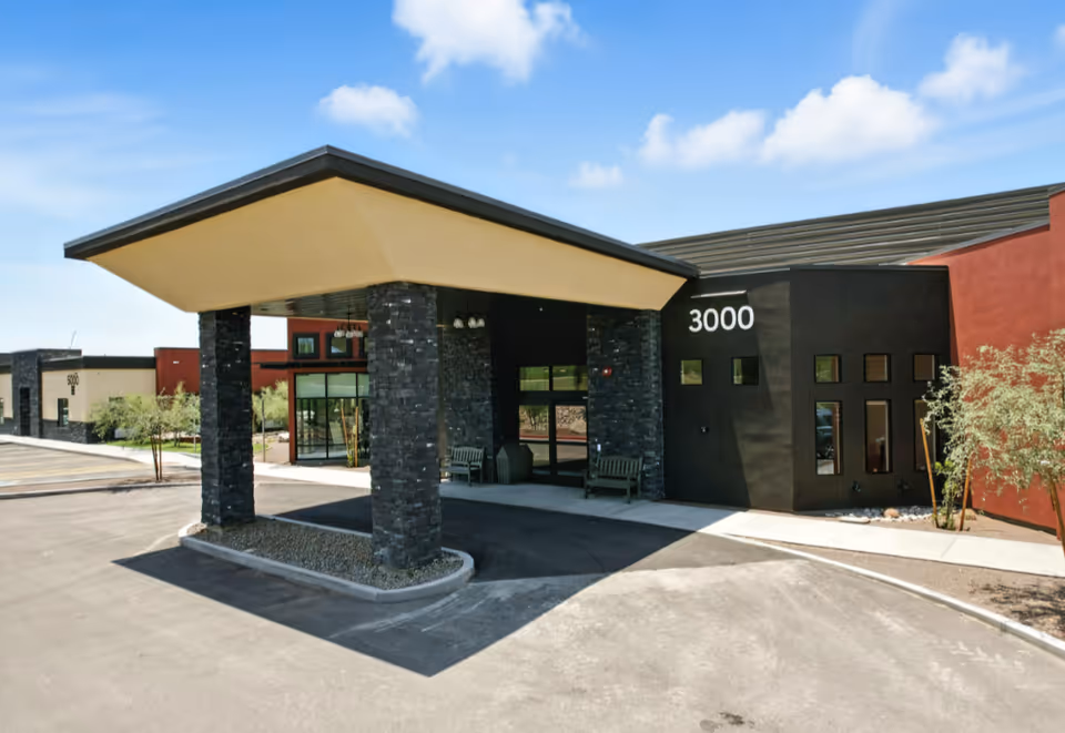 Exterior view of Cave Creek Assisted Living entrance with a covered drop-off canopy and benches.