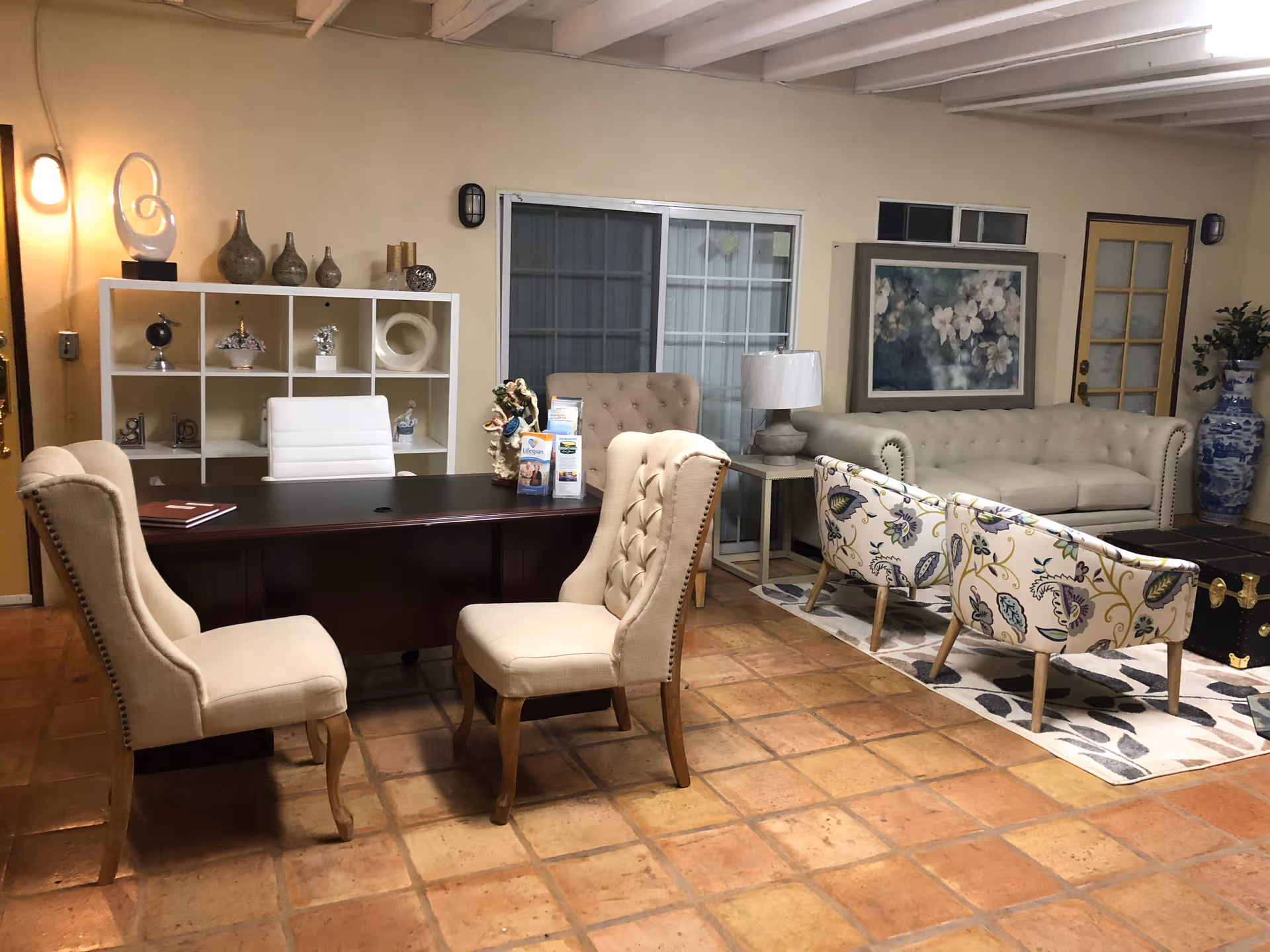 Spacious beige living area with a desk, chairs, sofas, and decorative shelving.