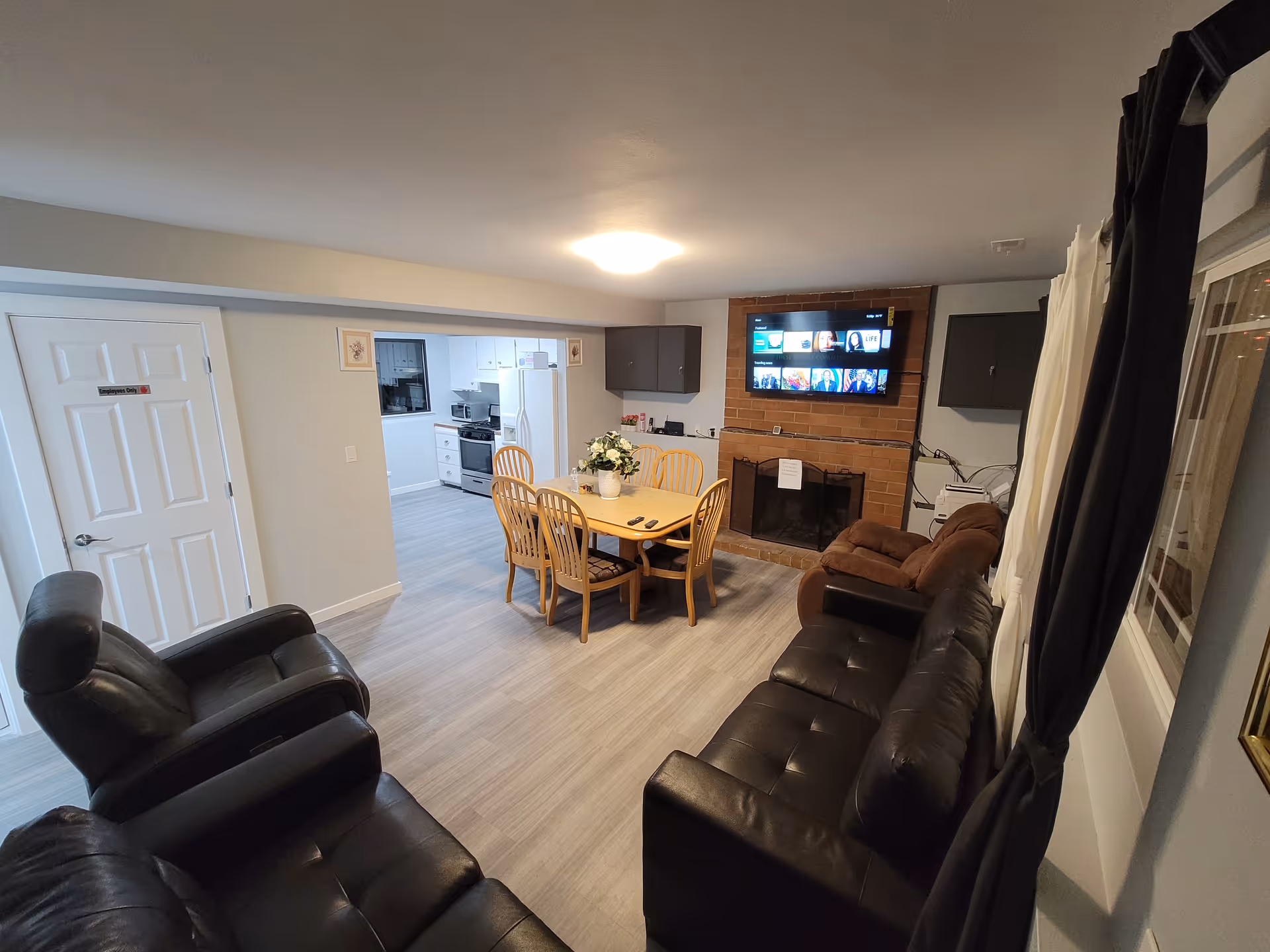Cozy living room with leather sofas, dining table, and a mounted TV above a brick fireplace.