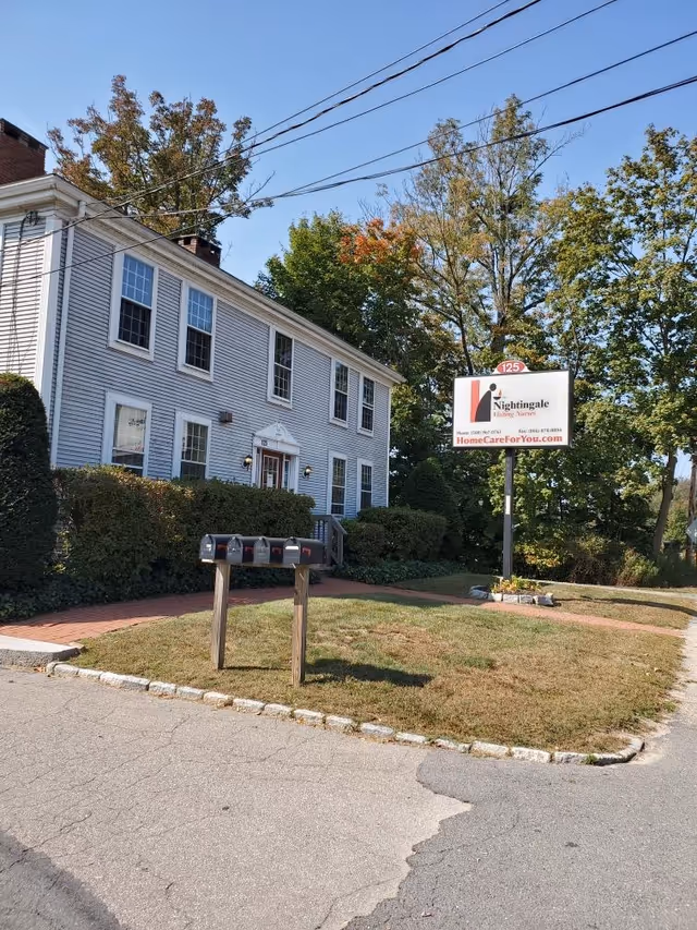 White two-story building with Nightingale Visiting Nurses sign and trees