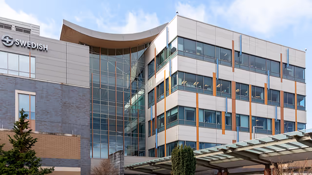Exterior view of a modern Swedish medical facility with a curved glass entrance.