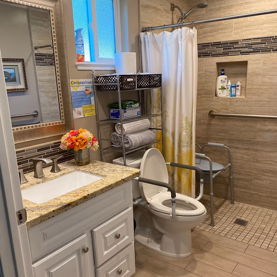 Accessible bathroom with toilet, sink, shower, grab bars, and storage shelves.
