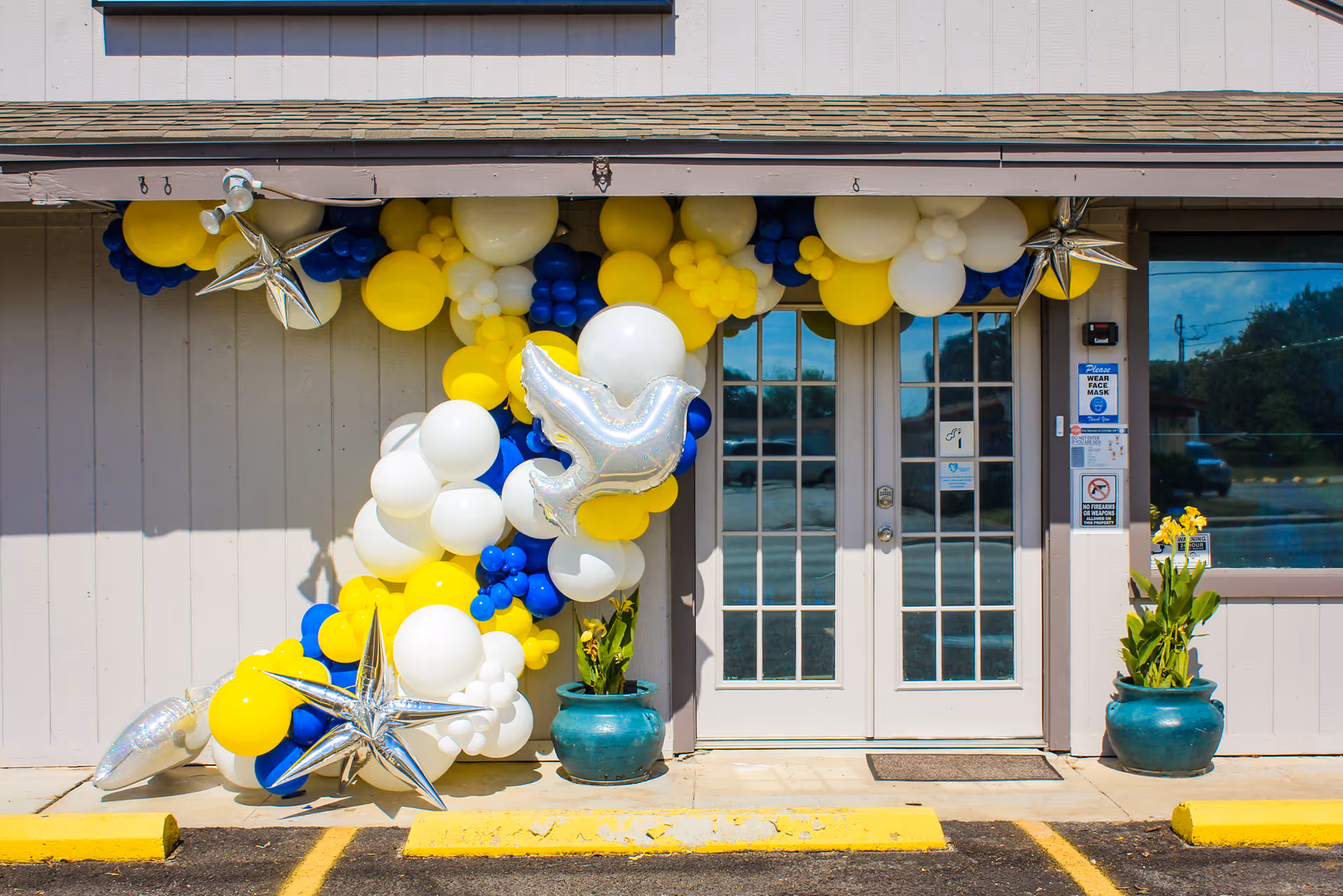 Front entrance of a facility decorated with blue, yellow, and white balloons.
