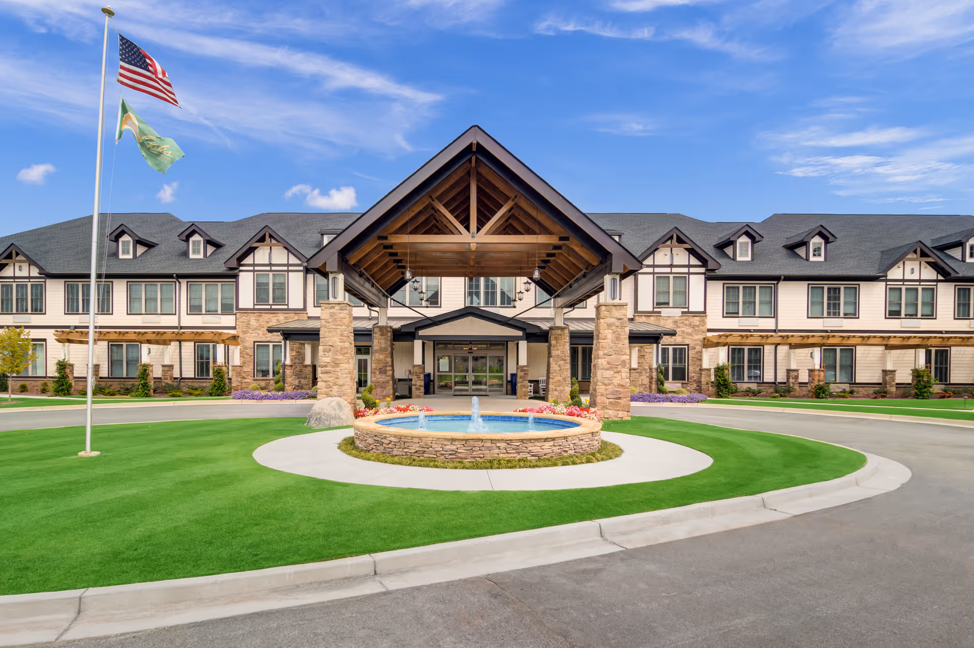 Large senior living facility exterior with a covered entrance and circular fountain driveway.