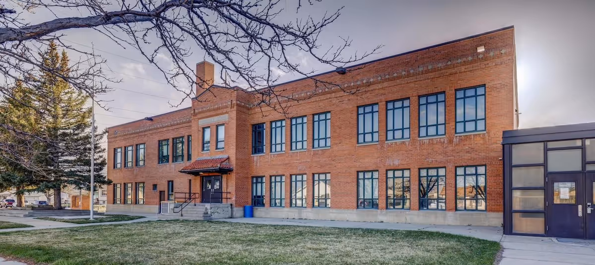 Brick two-story facility with large windows and a glass entry, set on a grassy lawn.