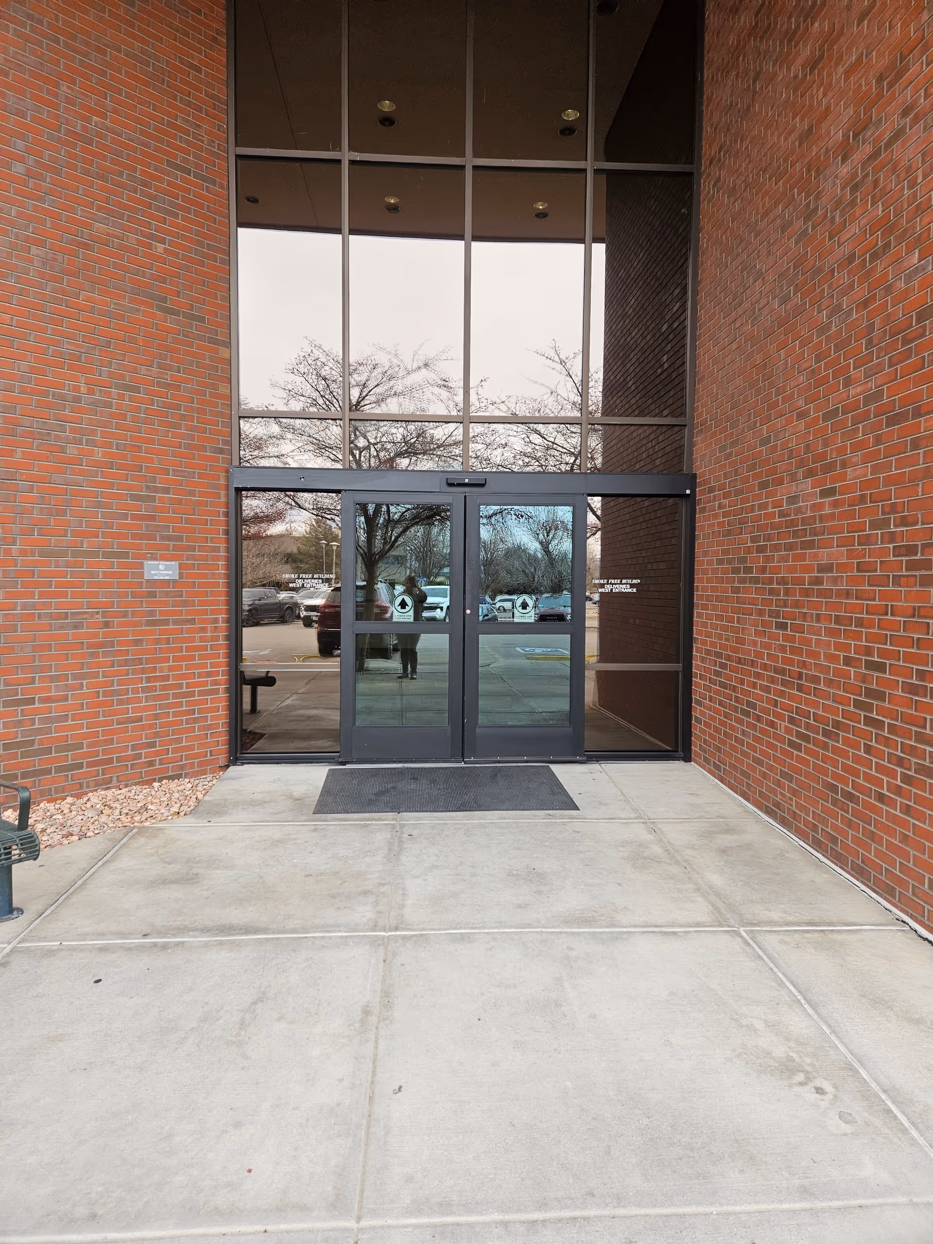 Brick exterior with tall glass doors and a concrete walkway.