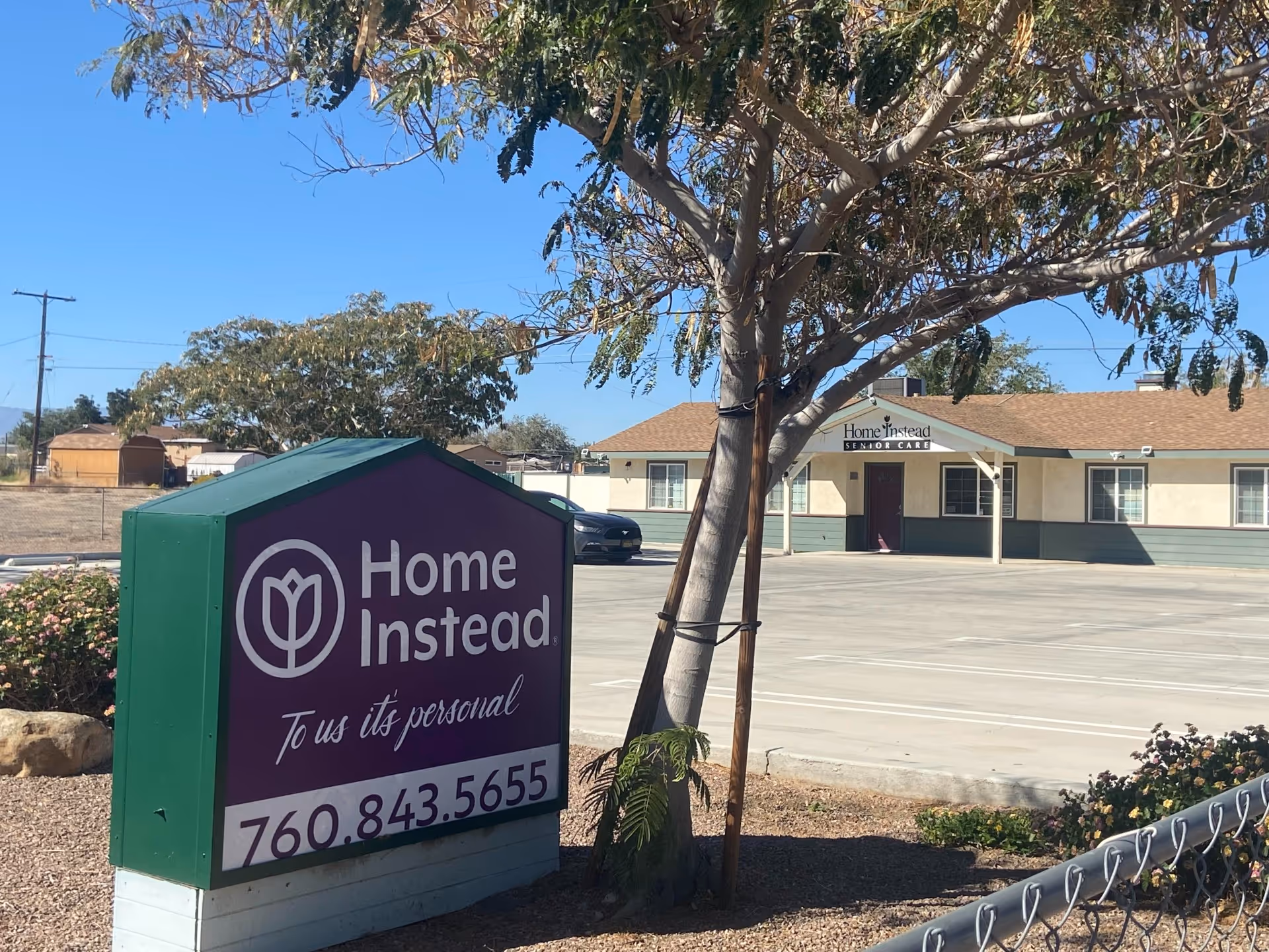 Exterior view of Home Instead Senior Care building with purple sign in parking lot.