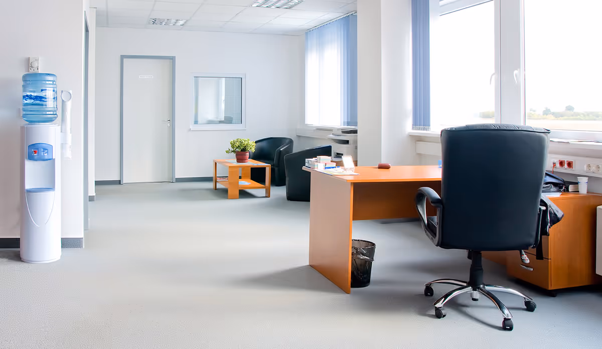 Bright office area in a senior facility with desk, chairs, water cooler, and windows.
