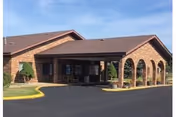 Brick senior living facility with arched entrance and covered portico.