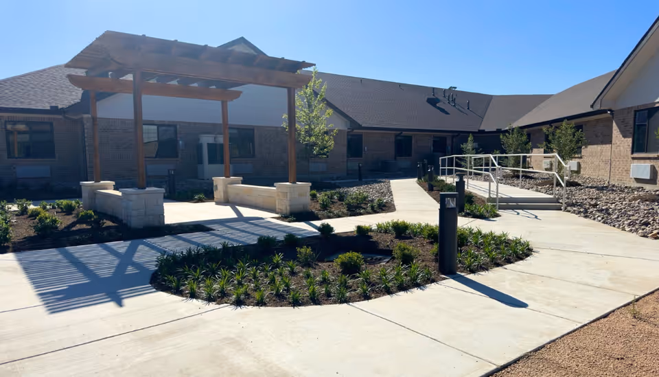 Exterior view of Avir at Kerrville with a landscaped courtyard and wooden pergola.