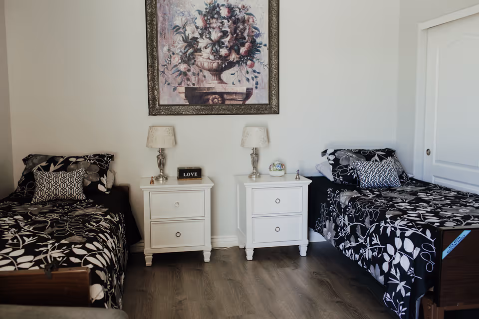 Two twin beds with matching black-and-white floral bedding flank white nightstands.