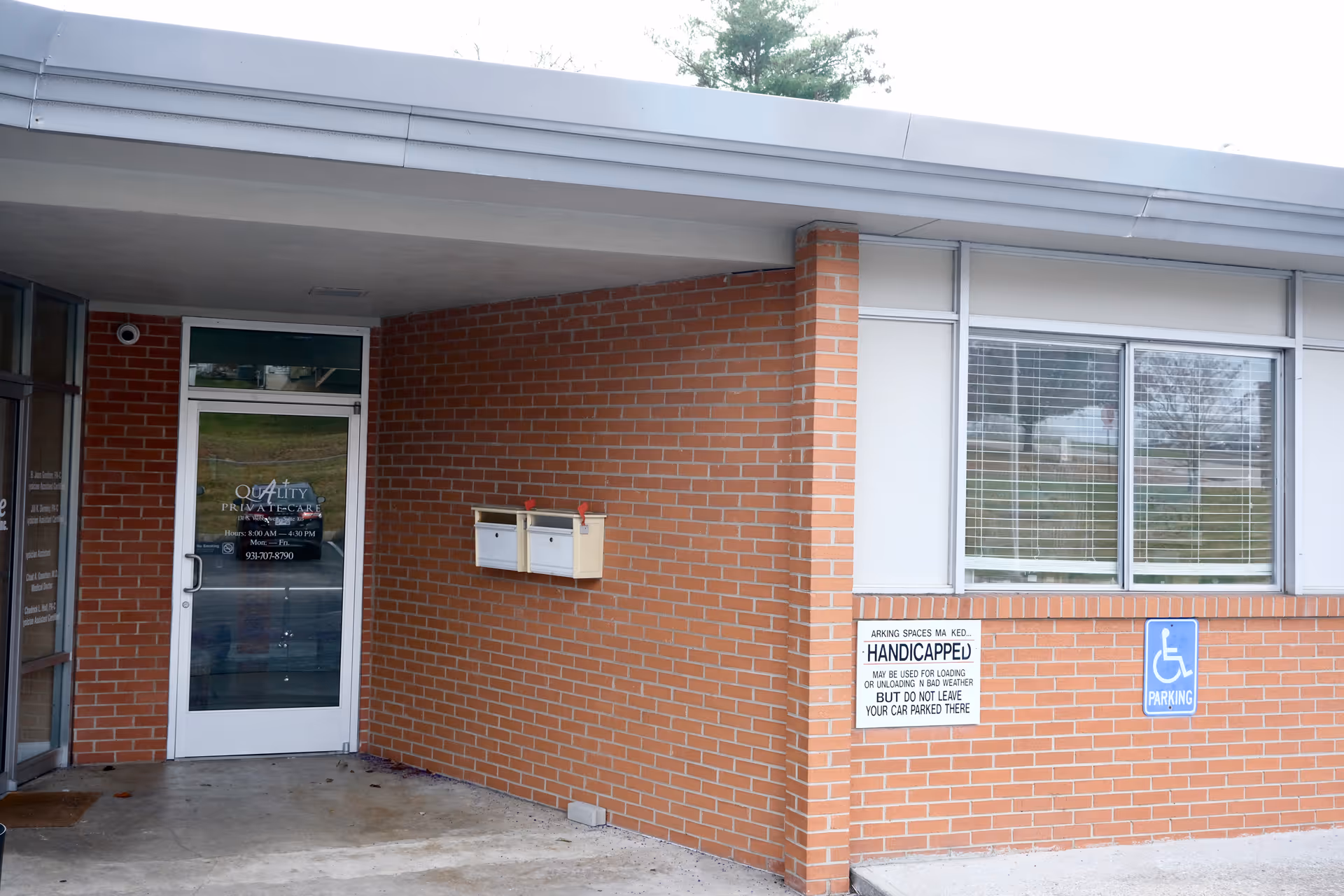 Exterior brick entrance of Quality Private Duty Care with a door, mailbox, window, and handicap sign.
