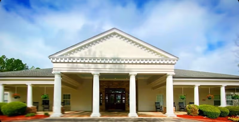 Front view of a beige senior living facility with columns and a covered entrance.