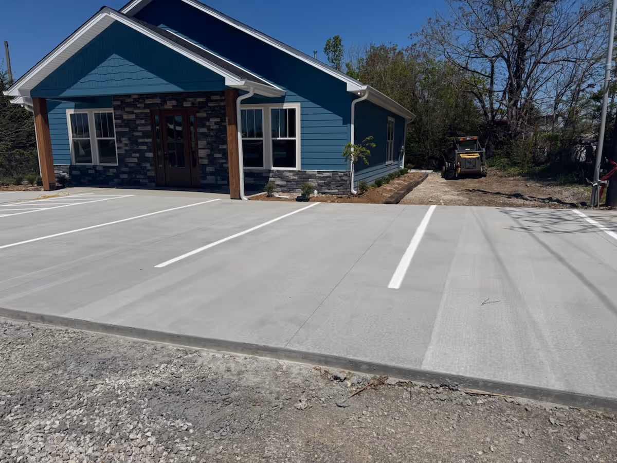 Blue modern building with stone accents, fresh parking lot, and construction area behind.