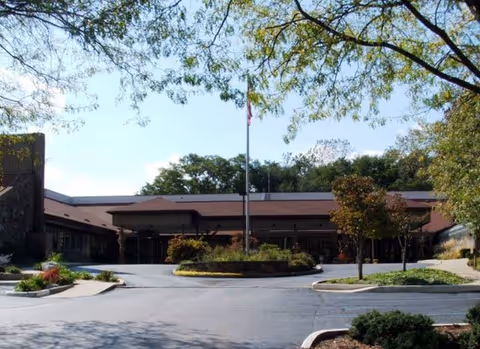 Meadowood senior living facility exterior with circular drive and flagpole.