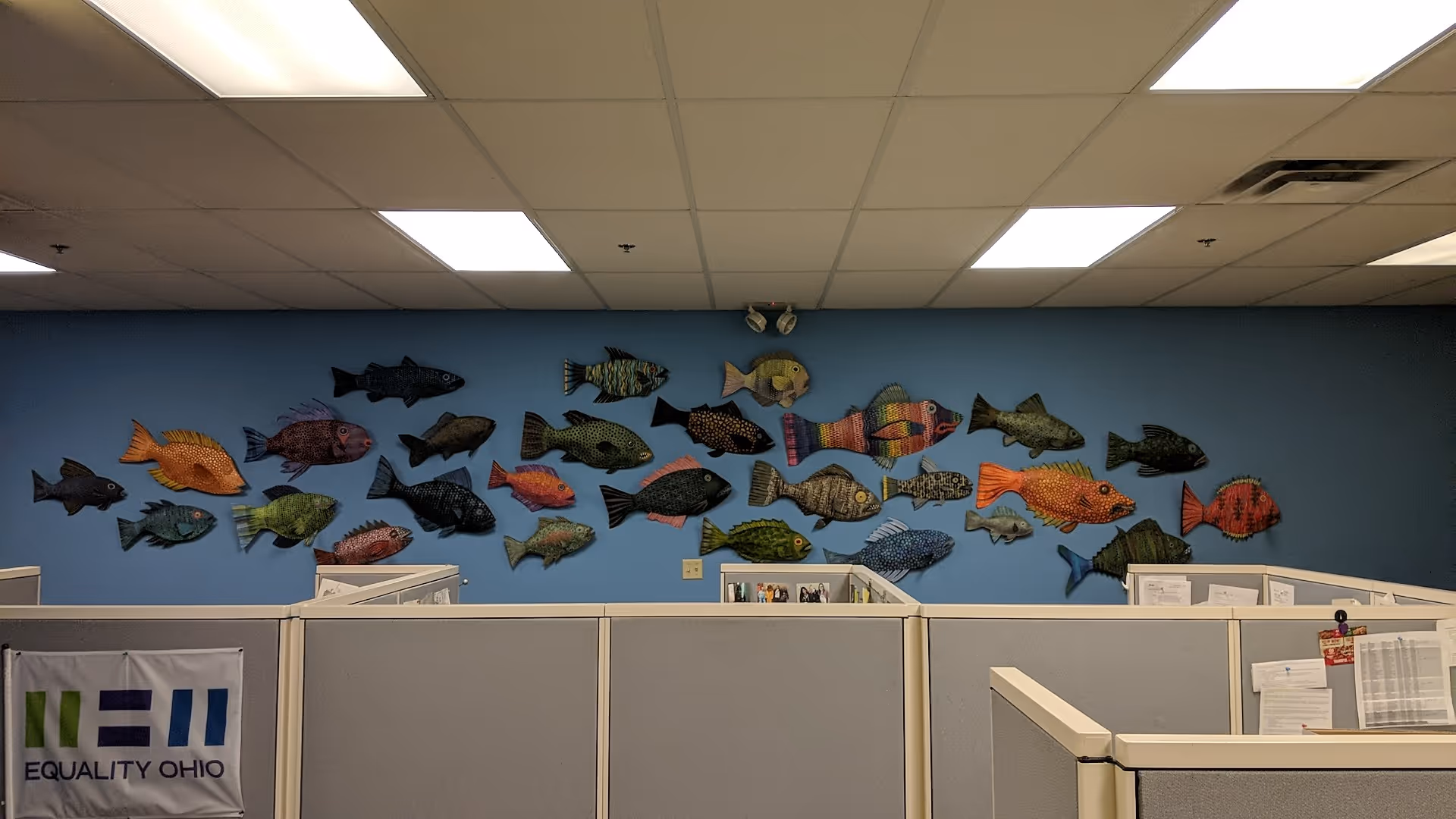 Indoor office-like cubicle area with a blue wall mural of colorful fish decorations.