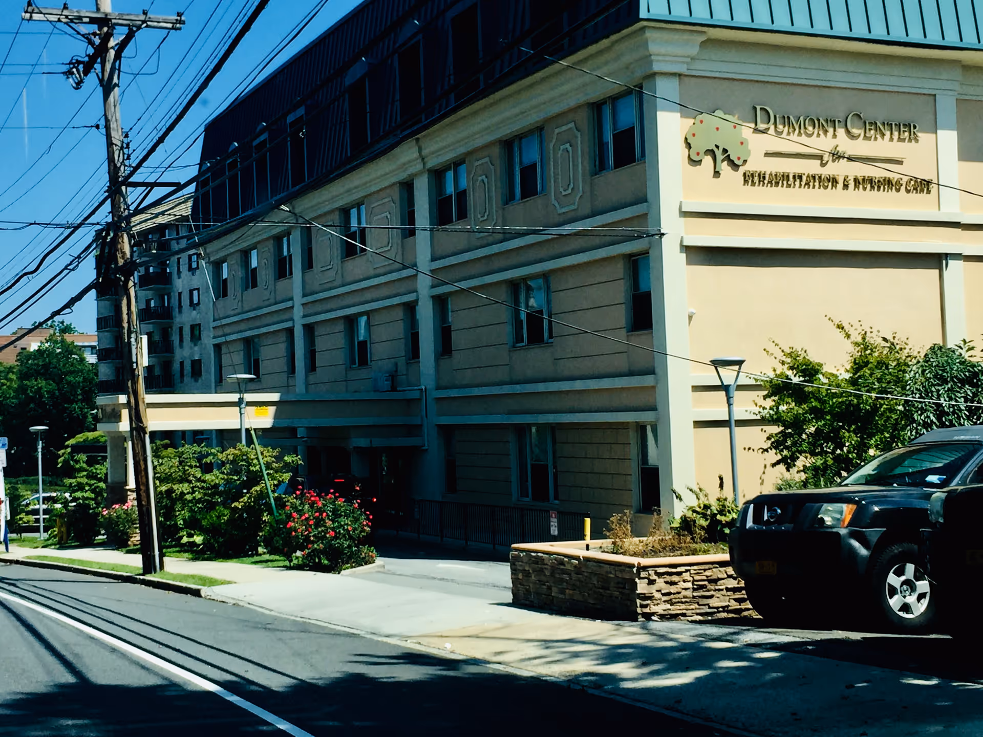 Exterior view of a multi-story senior living facility with a Dumont Center sign.