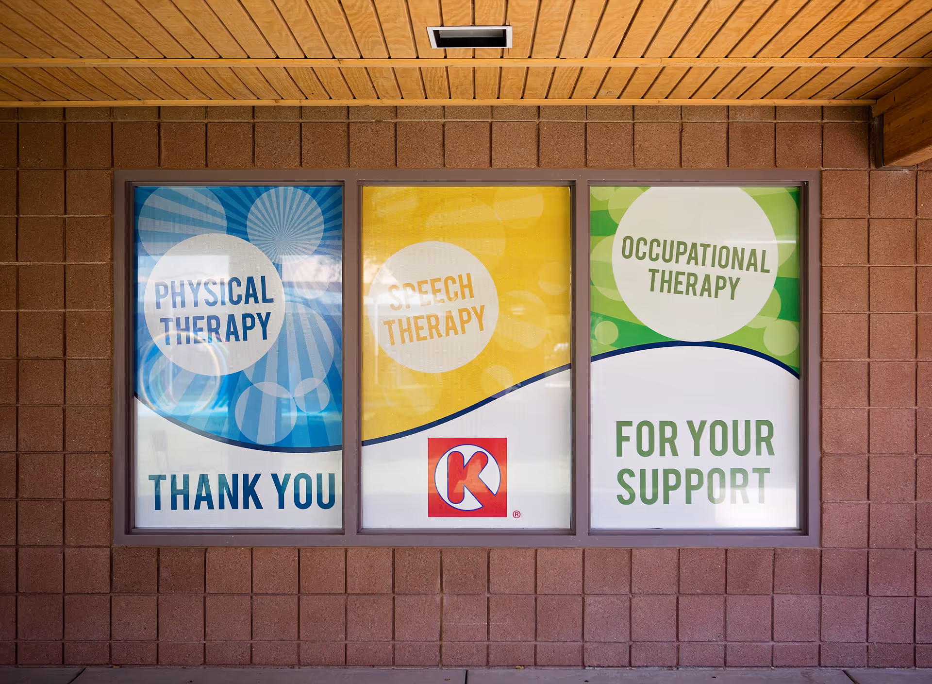 Three therapy program posters displayed in a window on a brick exterior wall.