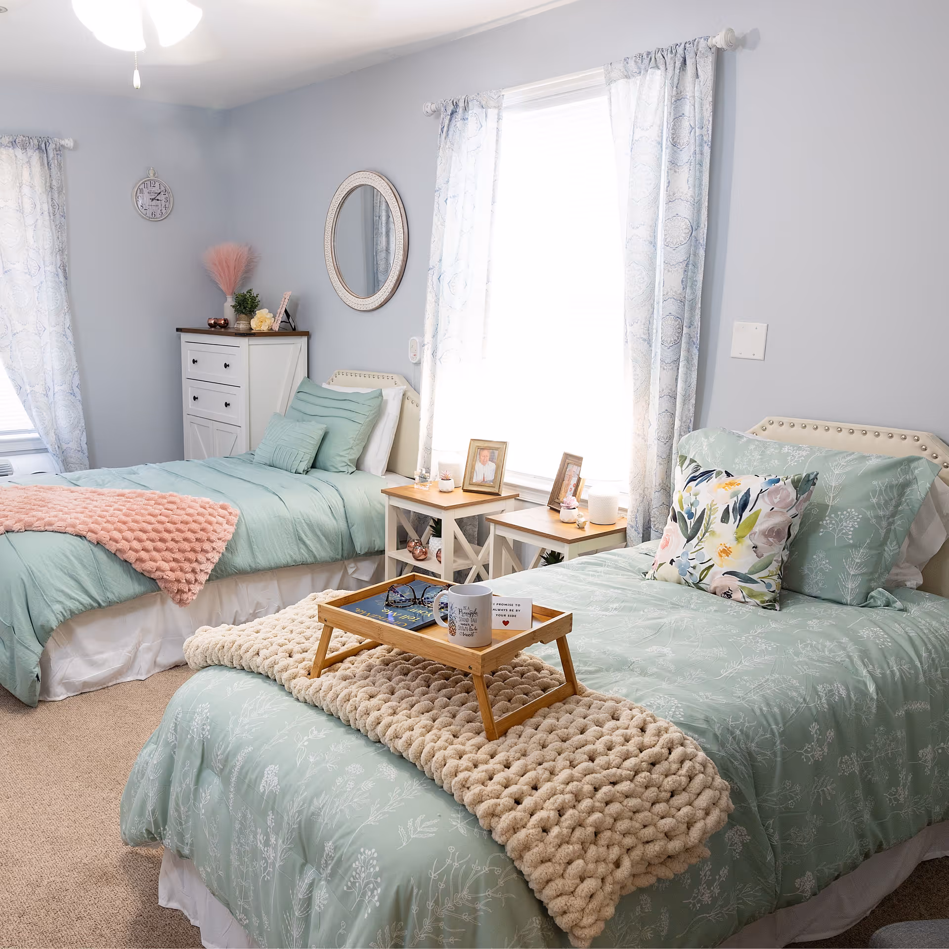 Two twin beds with mint-green bedding and cozy decor in a bright, calm bedroom.