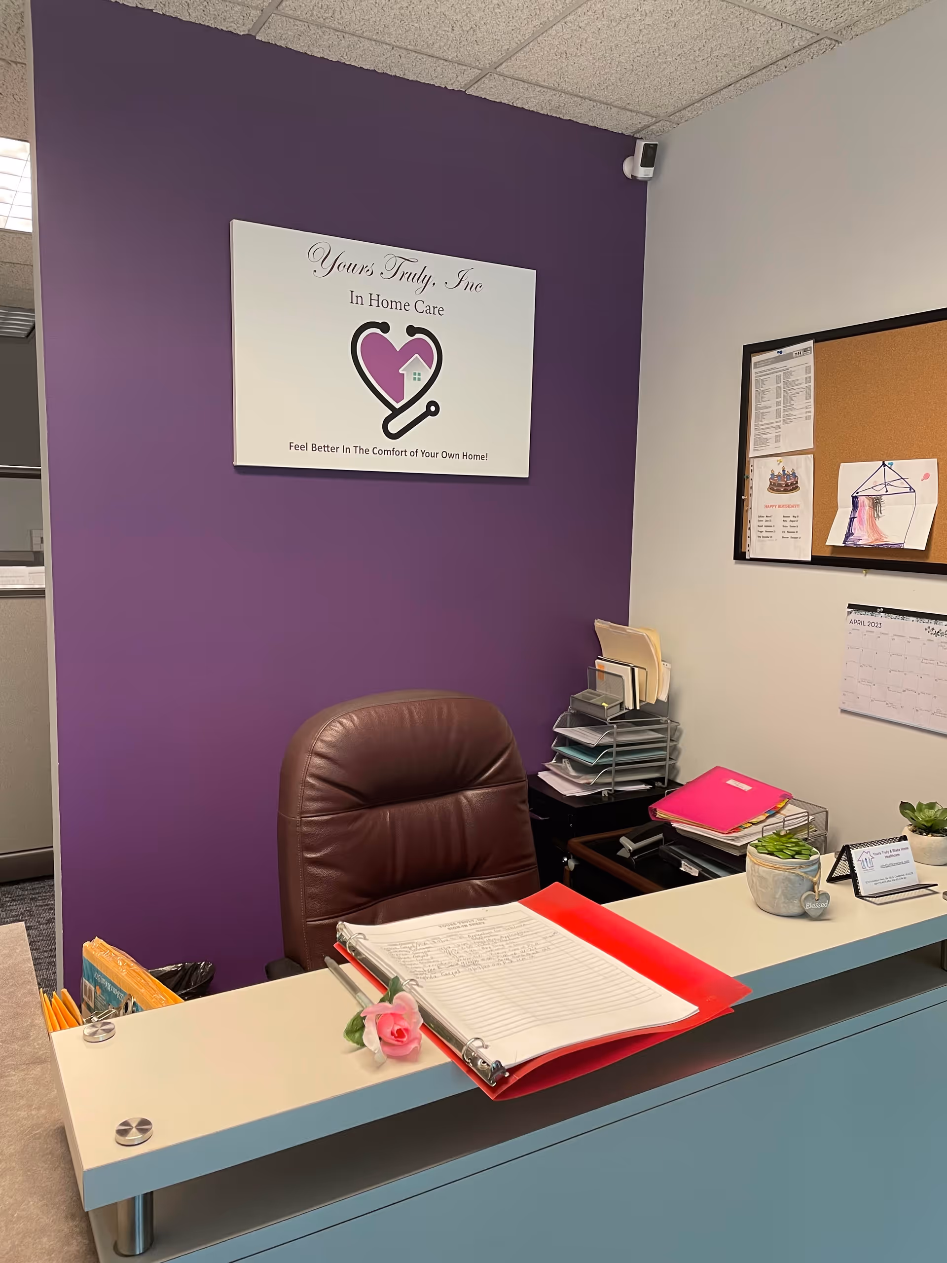 Reception desk in an office with purple wall and Yours Truly, Inc In Home Care sign.