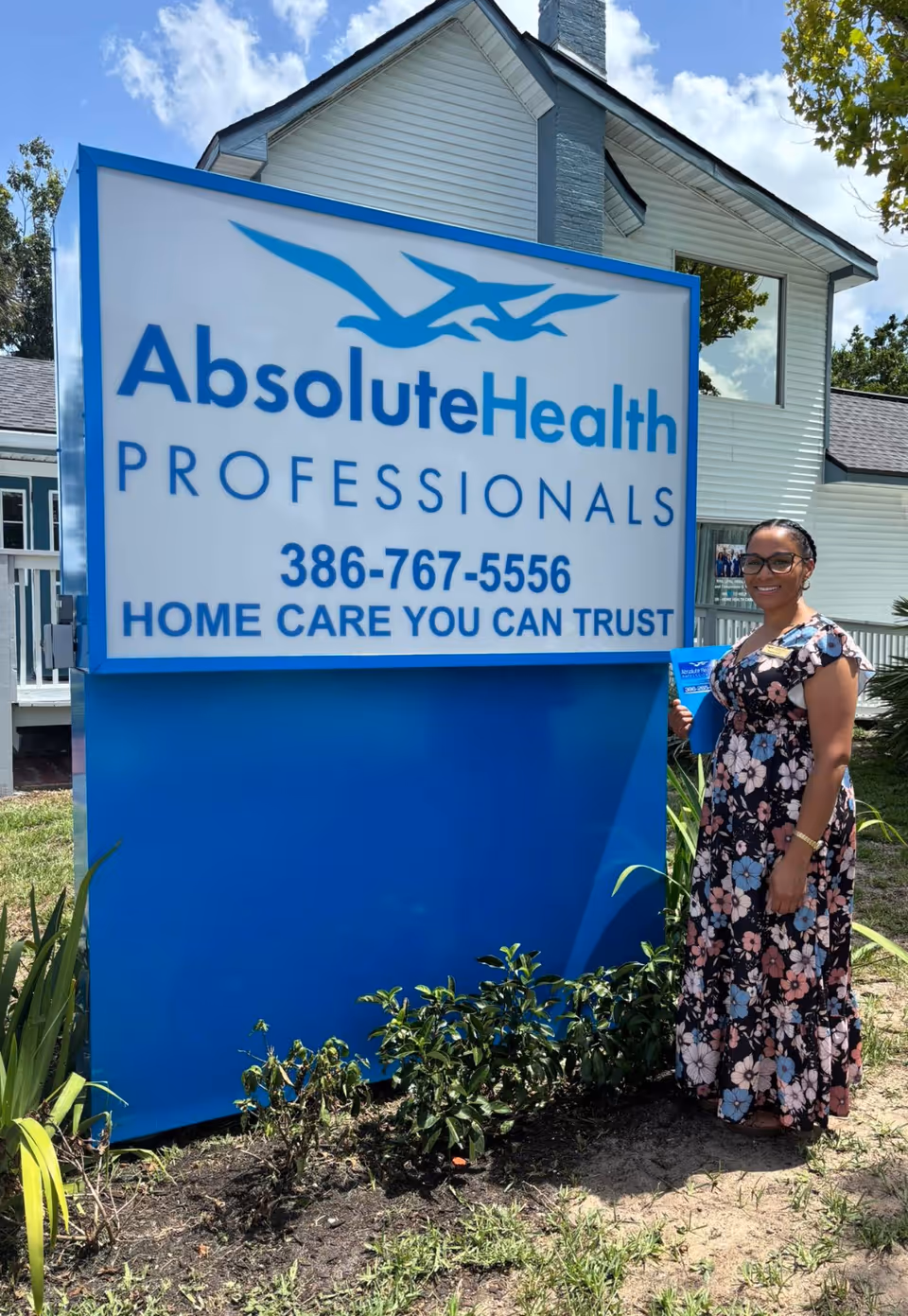 A large blue AbsoluteHealth sign stands beside a woman outside a building.