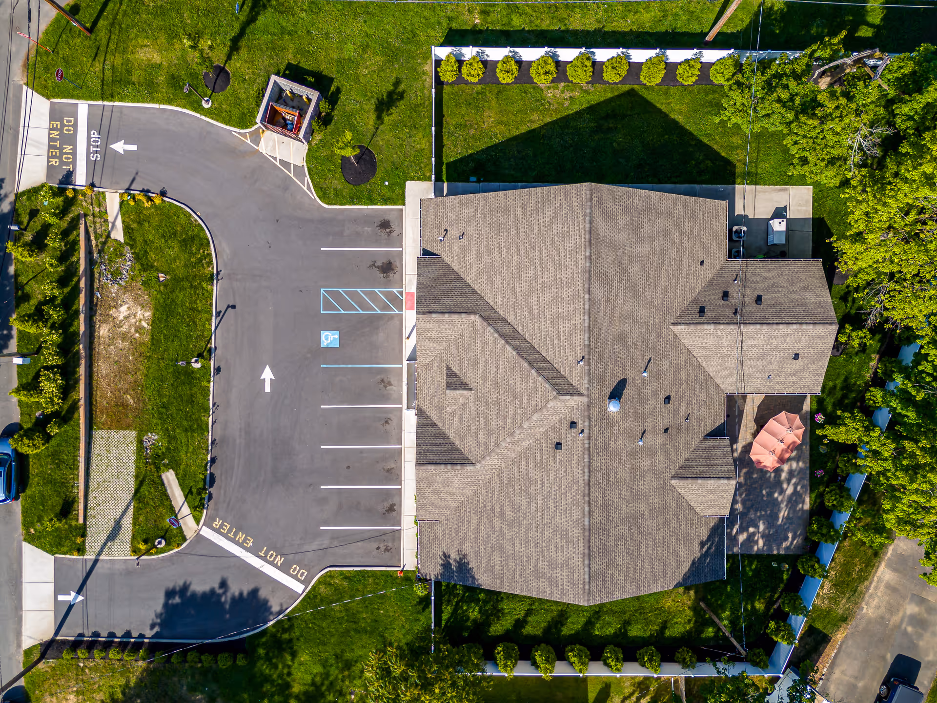 Aerial view of Peaceful Pines: beige-roofed building, parking lot, and green landscaping.