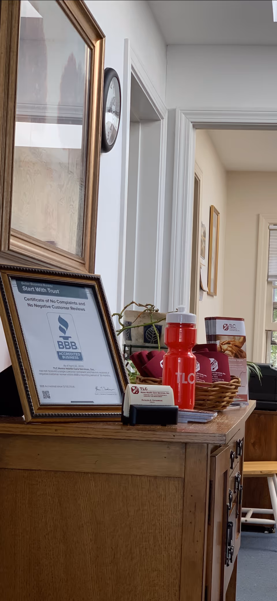 Reception desk with framed certificates, TLC brochures, red water bottle, and wall art.