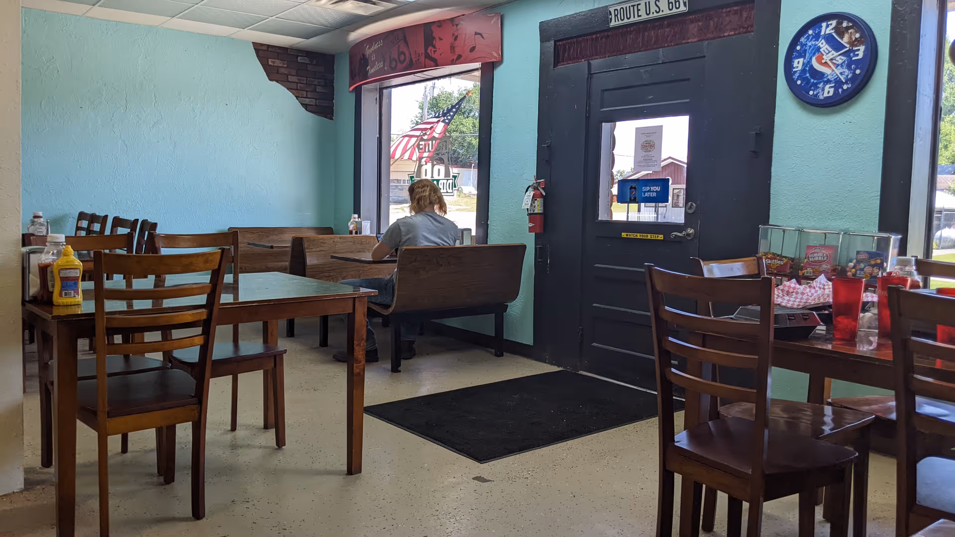 One person sits at a booth in a cozy dining area inside a senior living facility.