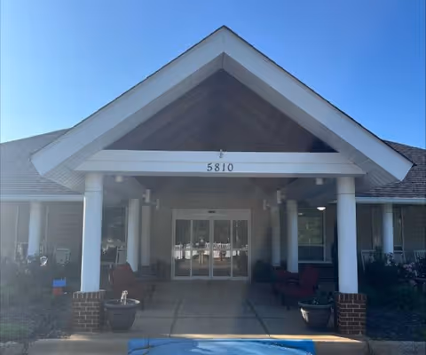 Front entrance of a senior living facility with a peaked roof and glass doors.