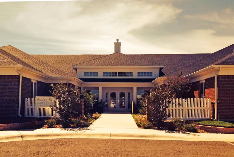 Front entrance of Turning Brook III senior living facility with a sidewalk and white picket fences.