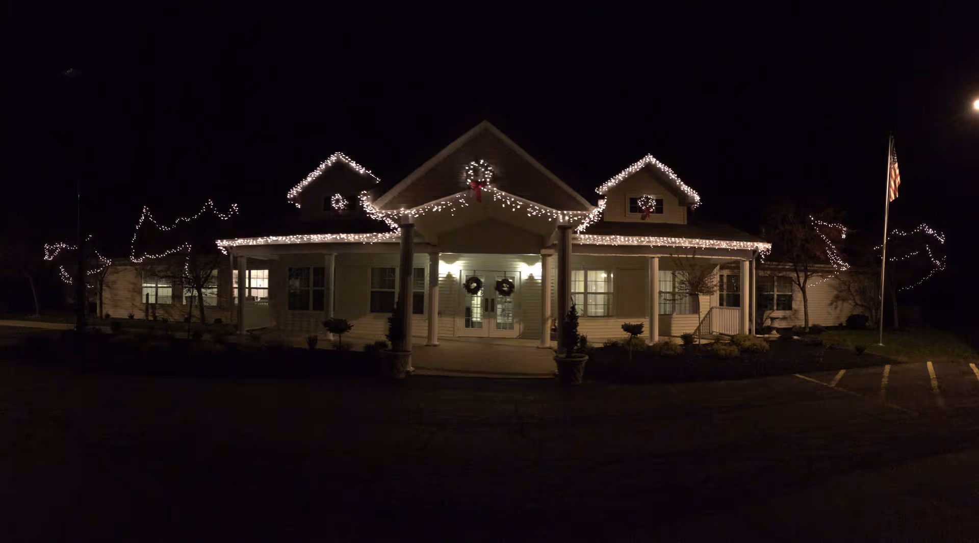 Night view of Trustwell Living at Carlisle Place building lit with string lights and wreaths.