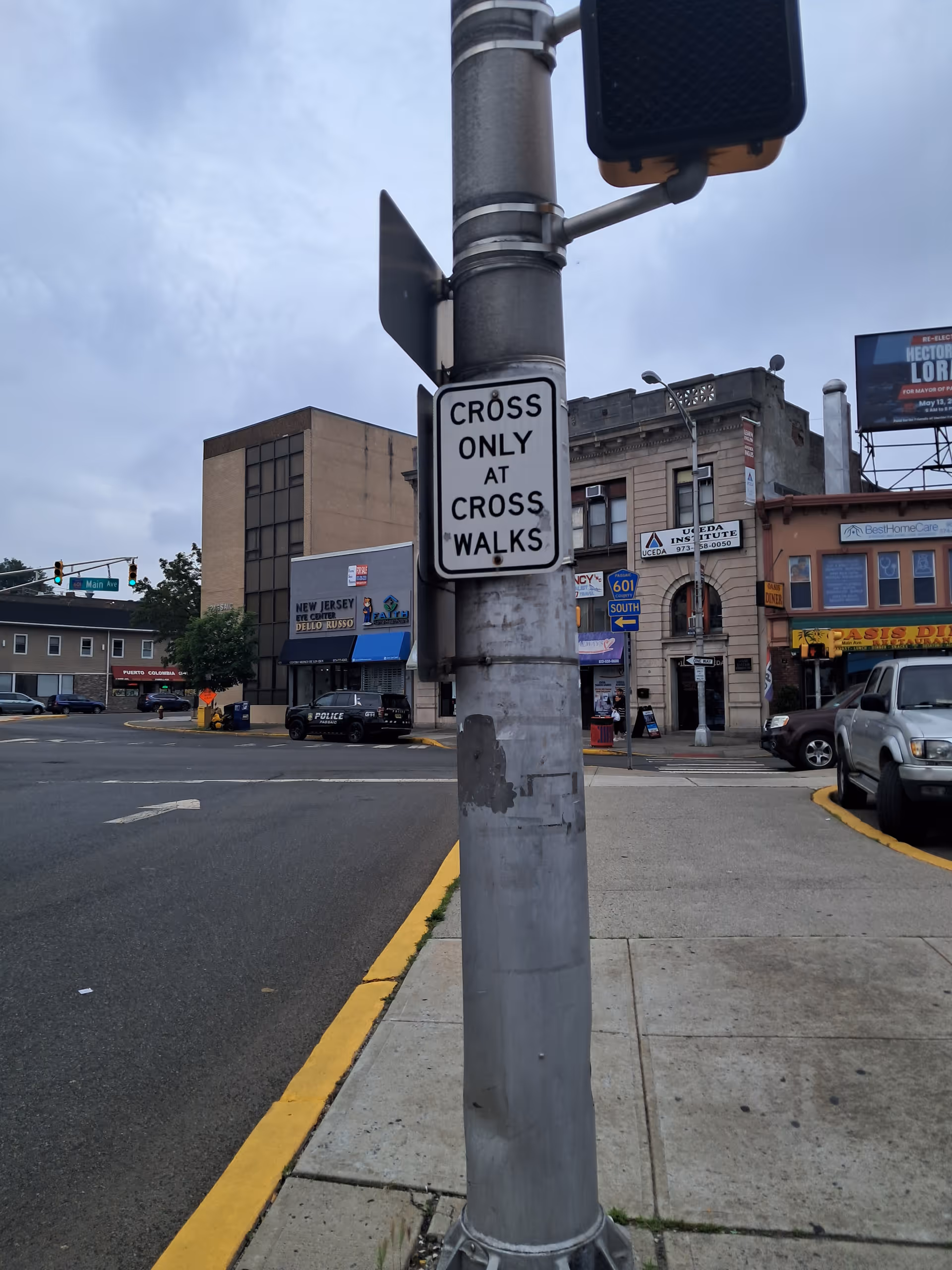 A foreground utility pole with a sign and background brick buildings and storefronts.