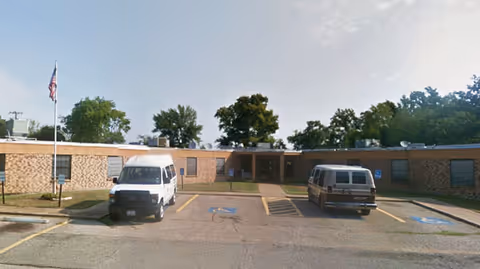 Montessori Senior Residential Care facility exterior: single-story brick building with two vans in front.