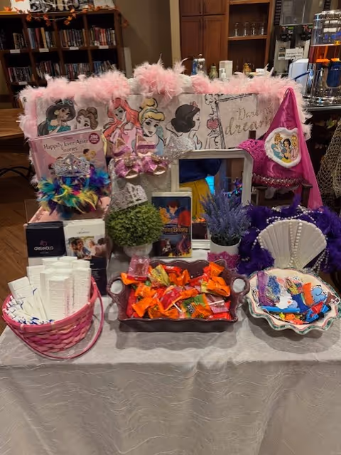 Princess-themed party display with candy, feathers, and decorative items on a table.