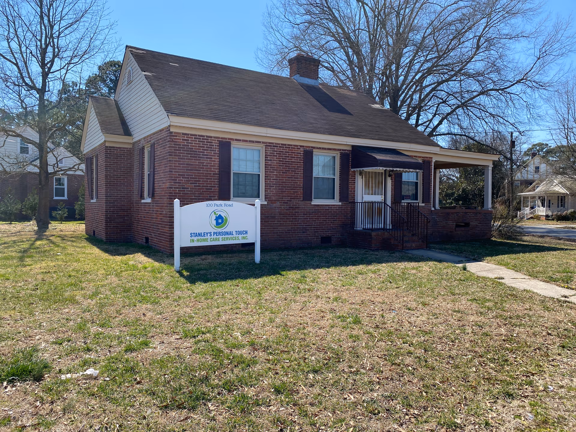 Brick, single-story building with a Stanley's Personal Touch sign, front yard, and sidewalk.