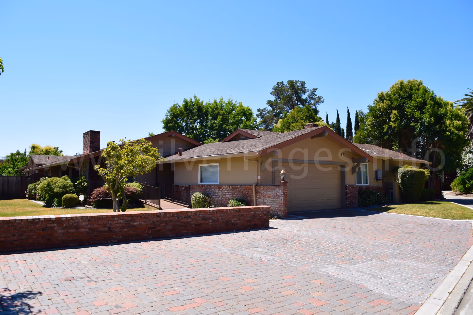 Single-story senior residence with brick accents, a curved brick driveway, and landscaped front yard.