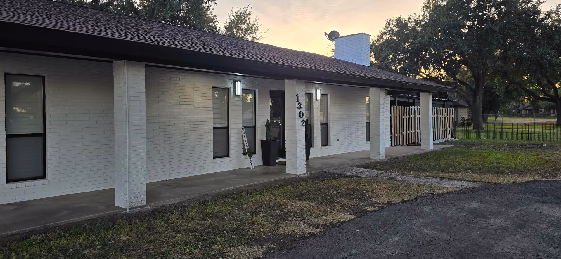 White brick building exterior with a covered porch and pillars.