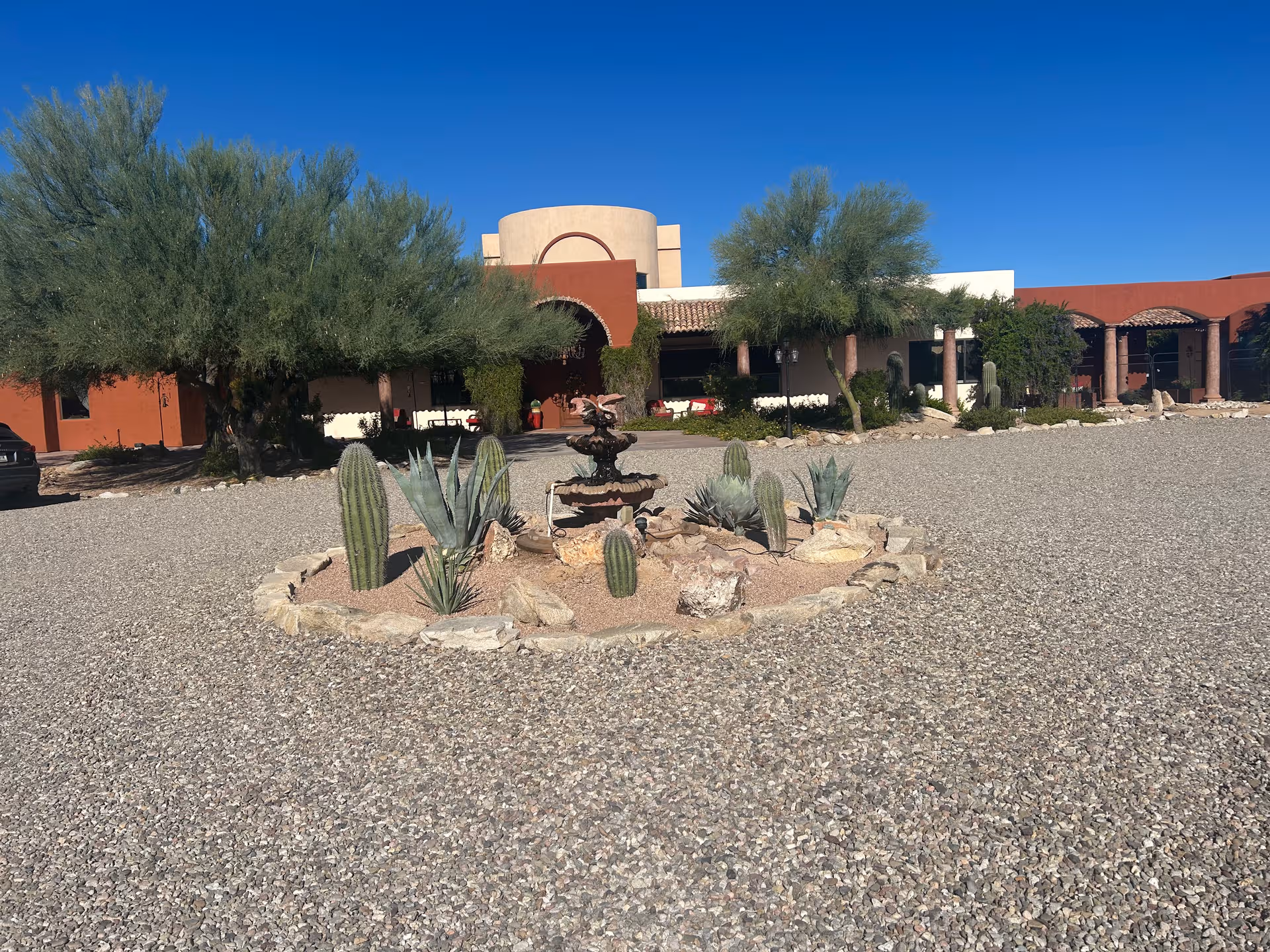 Exterior view of Saguaro Ranch Luxury Assisted Living with desert landscaping and a fountain.