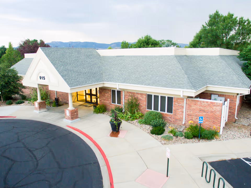 Brick senior living facility with a covered front entrance and surrounding landscaping