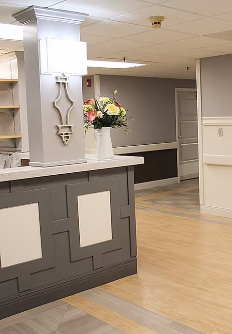Gray reception desk with a vase of flowers in The Villa at Texarkana lobby.
