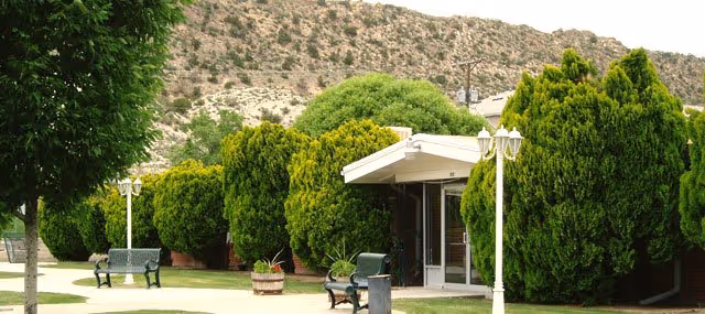 Exterior view of Skyline Ridge Nursing and Rehabilitation Center entrance with trees and benches.