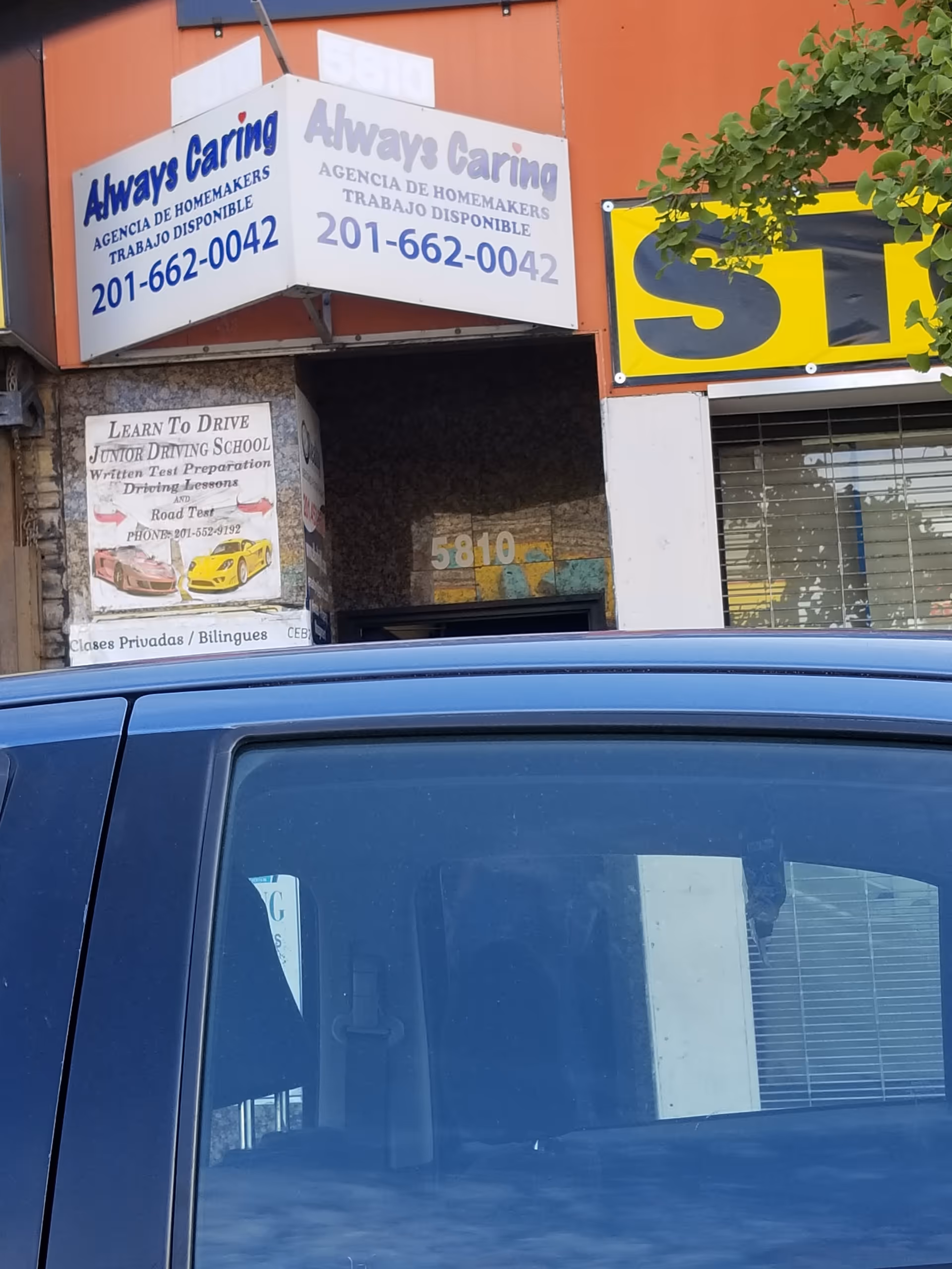 Storefront with Always Caring signs above, and a blue vehicle parked in front.