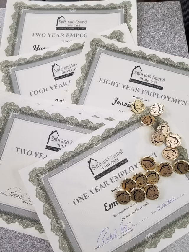 Close-up of Safe and Sound Home Care certificates and coins on a desk.