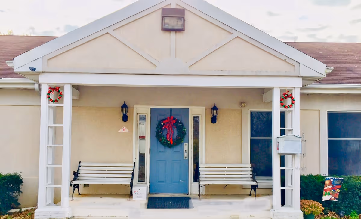 Front entrance of a senior living facility featuring a blue door and wreath.