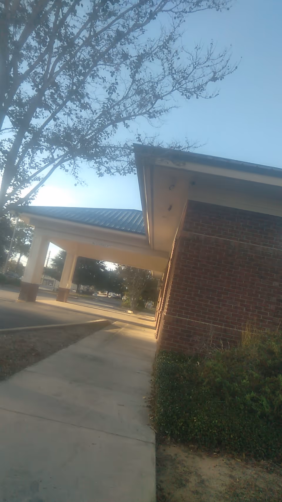 Brick building exterior with a covered entrance and sidewalk.