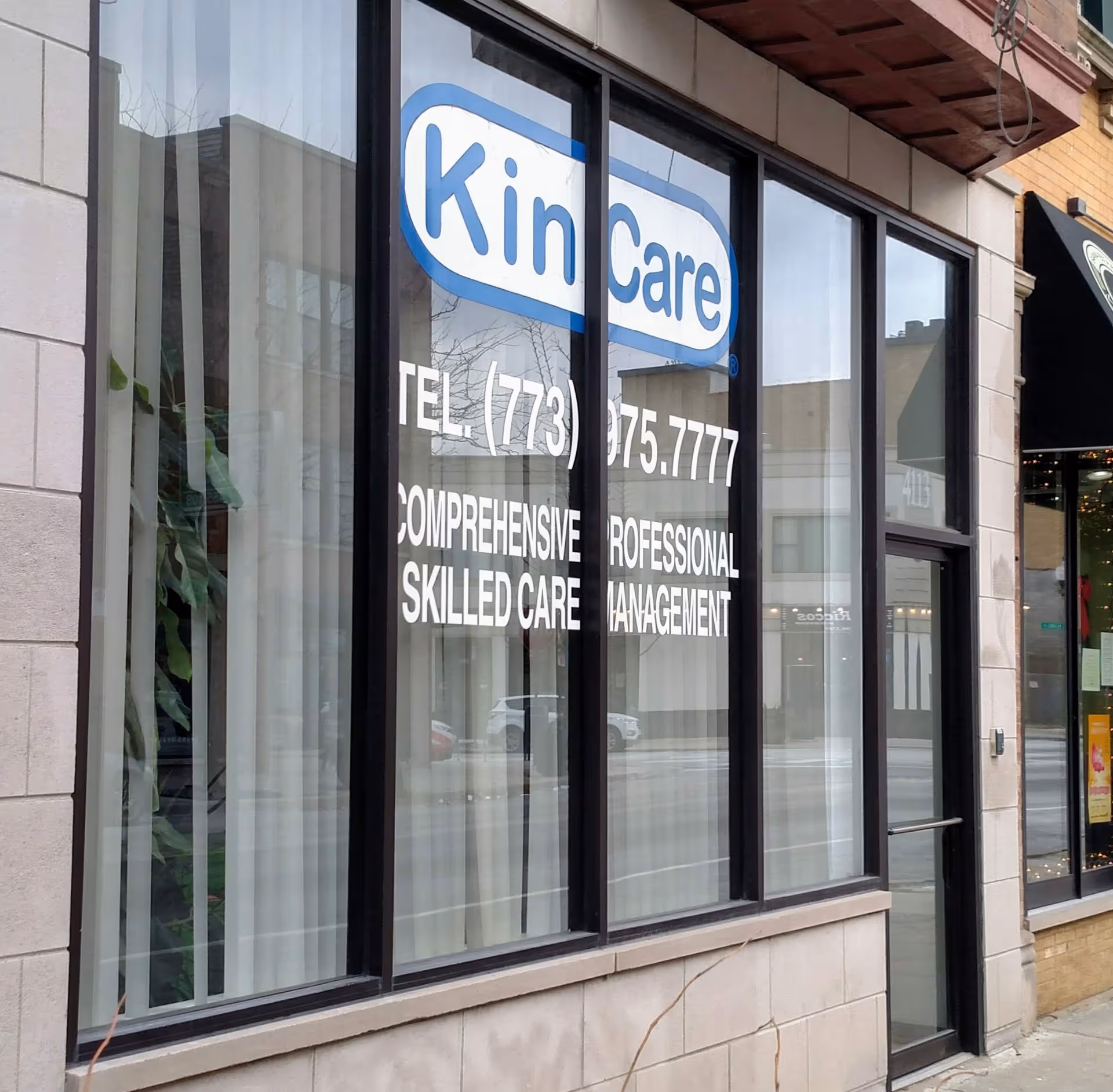 Kin Care storefront with large window sign and contact information on the glass.