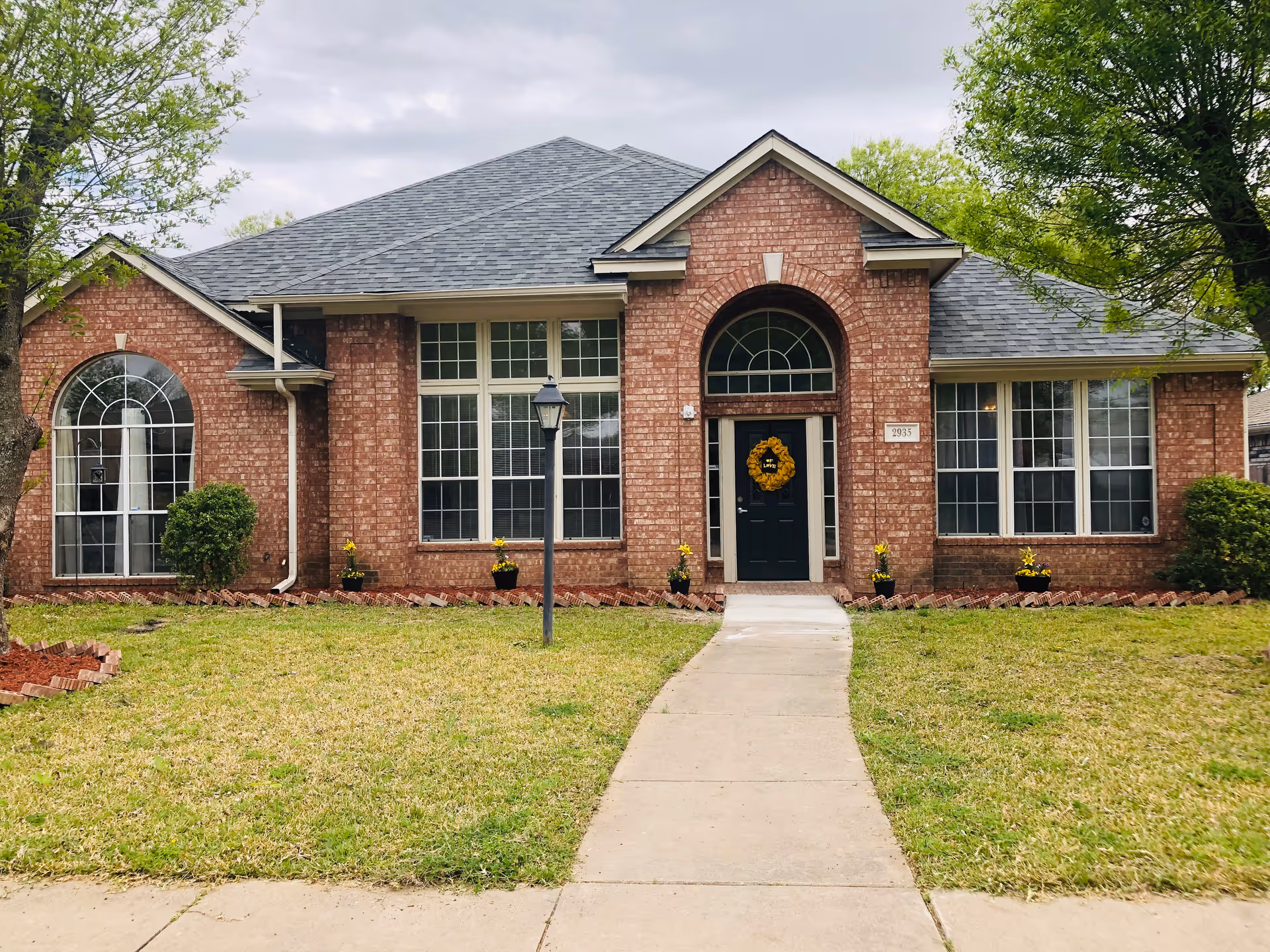 Brick senior living facility with arched windows and a central doorway on a grassy lawn.
